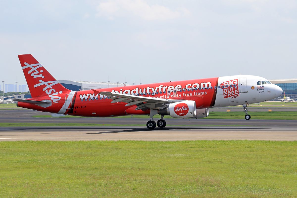 AirAsia Airbus A320 aircraft landing on an airport runway on a bright sunny day