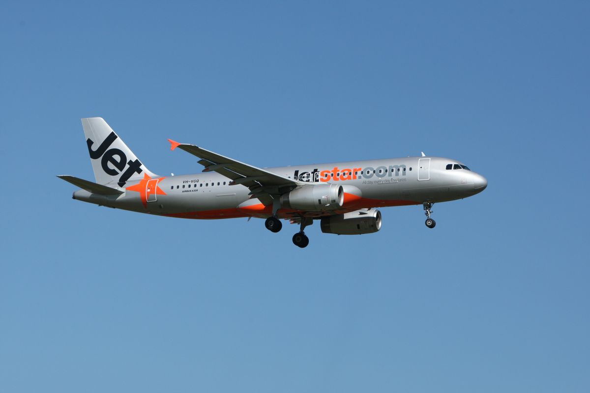 Jetstar Airbus A320 aircraft flying against a clear blue sky — low-cost carrier